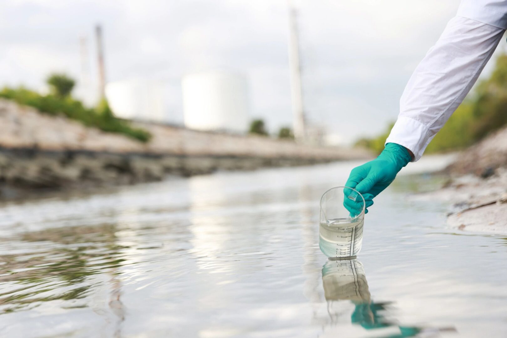 Person collecting water sample from river.